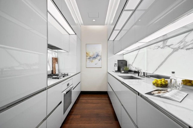 kitchen featuring sink, white oven, white cabinetry, dark hardwood / wood-style floors, and stainless steel gas stovetop