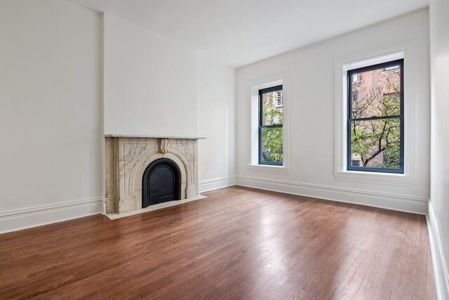 unfurnished living room with hardwood / wood-style flooring, a tile fireplace, and an inviting chandelier