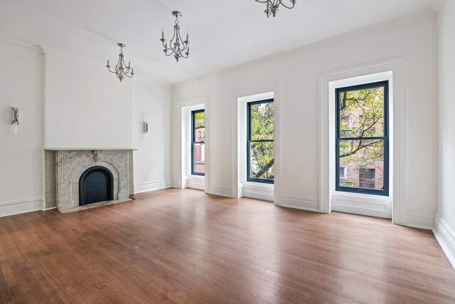 235 E 31st St, New York City, NY 10016 - unfurnished living room featuring a chandelier, wood finished floors, crown molding, a tile fireplace, and baseboards