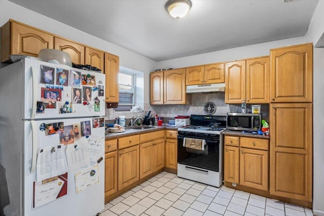 kitchen featuring sink, range with gas stovetop, white fridge, and tasteful backsplash