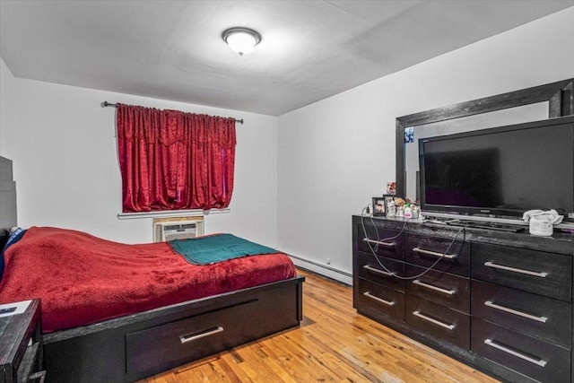 bedroom with light hardwood / wood-style floors and a baseboard heating unit