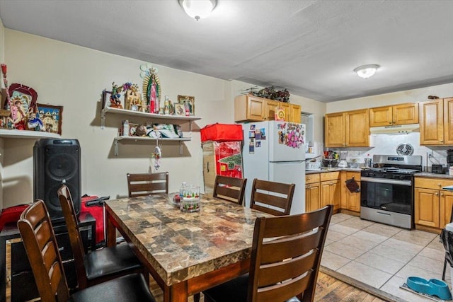 kitchen with light tile patterned flooring, white fridge, and stainless steel range with gas stovetop