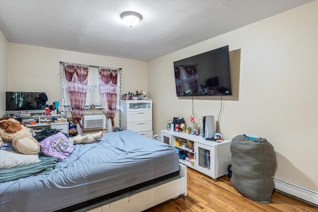 bedroom with light hardwood / wood-style floors, cooling unit, and a baseboard radiator