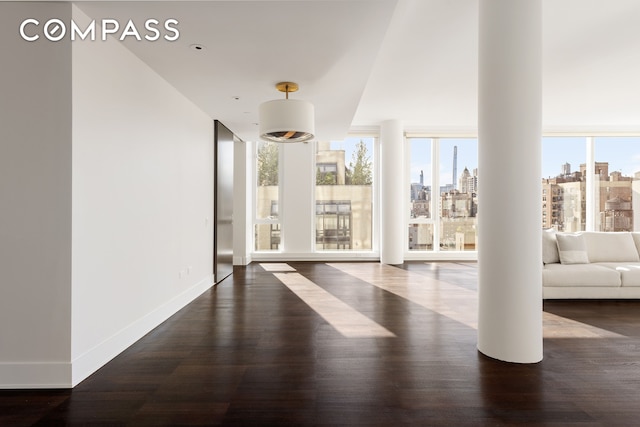 151 E 85th St Unit 14A, New York City, NY 10028 - unfurnished living room featuring healthy amount of natural light, dark wood-style floors, and a skyline view