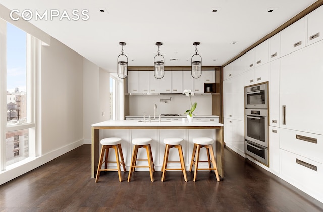 151 E 85th St Unit 14A, New York City, NY 10028 - kitchen featuring healthy amount of natural light, a sink, a kitchen bar, and dark wood-type flooring