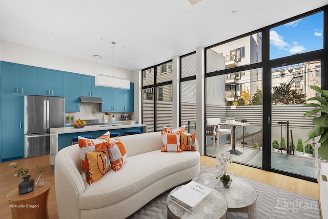 living area with light wood-type flooring, plenty of natural light, and floor to ceiling windows