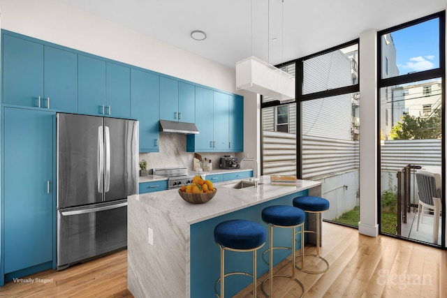 kitchen featuring a sink, appliances with stainless steel finishes, blue cabinetry, and under cabinet range hood