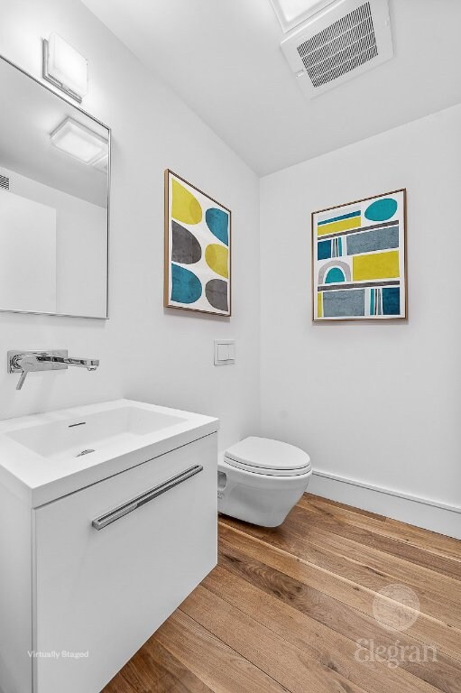 bathroom featuring hardwood / wood-style flooring, toilet, and vanity