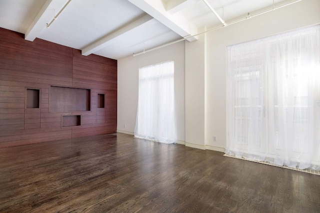 unfurnished living room with dark hardwood / wood-style floors, wooden walls, and beam ceiling