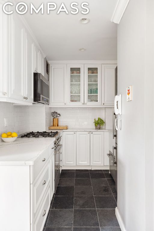 kitchen with white cabinets, backsplash, and appliances with stainless steel finishes