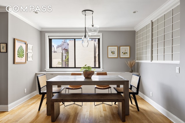 dining space featuring light wood-style floors and ornamental molding