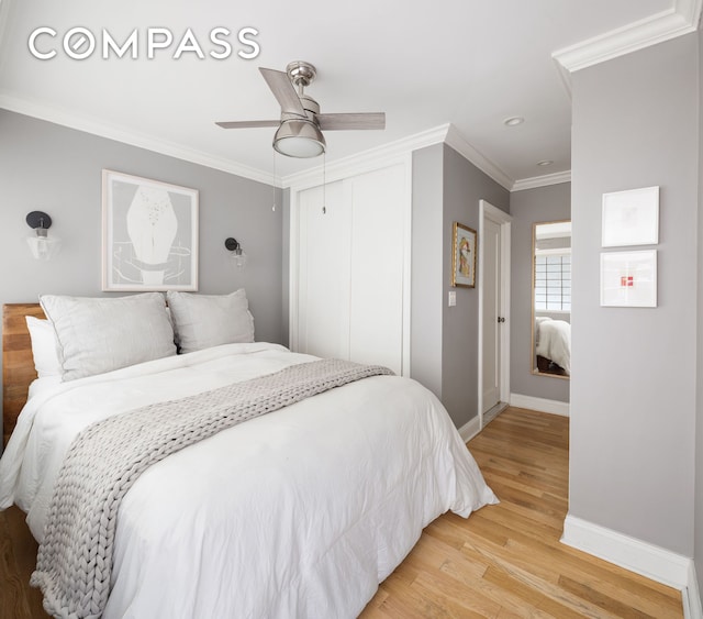 bedroom featuring ceiling fan, baseboards, ornamental molding, light wood-style floors, and a closet