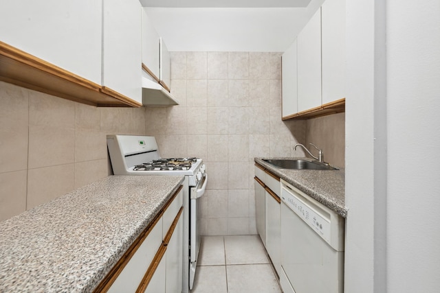 kitchen featuring white appliances, light tile patterned floors, a sink, white cabinetry, and tile walls