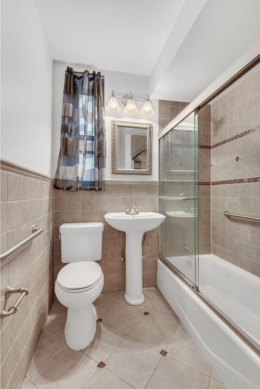 full bathroom featuring tile walls, tile patterned floors, enclosed tub / shower combo, and toilet