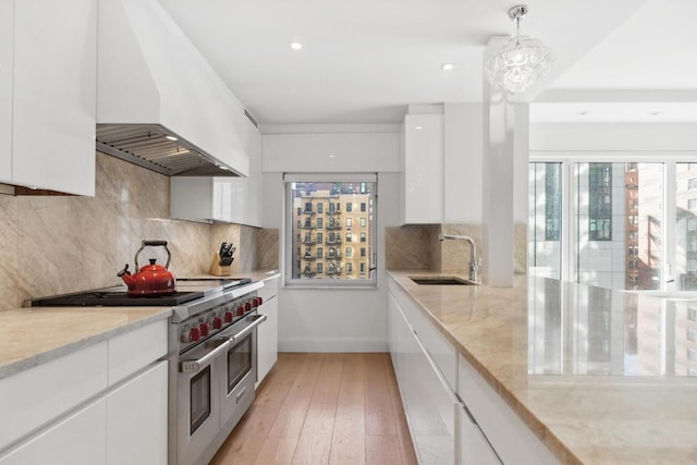 kitchen with sink, hanging light fixtures, custom range hood, white cabinets, and range with two ovens