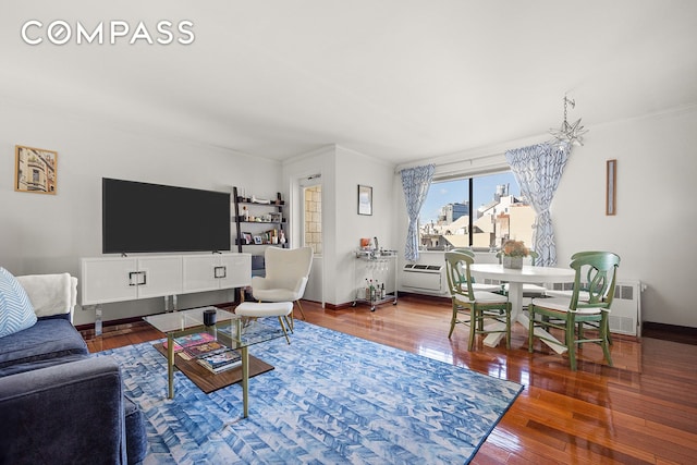 living room featuring baseboards, radiator, hardwood / wood-style floors, and crown molding