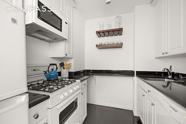 kitchen featuring white cabinetry, sink, white appliances, and dark tile patterned floors