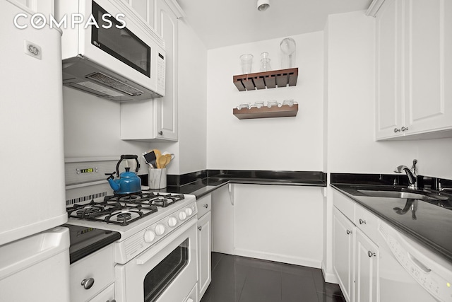 kitchen featuring dark countertops, a sink, white appliances, white cabinetry, and open shelves