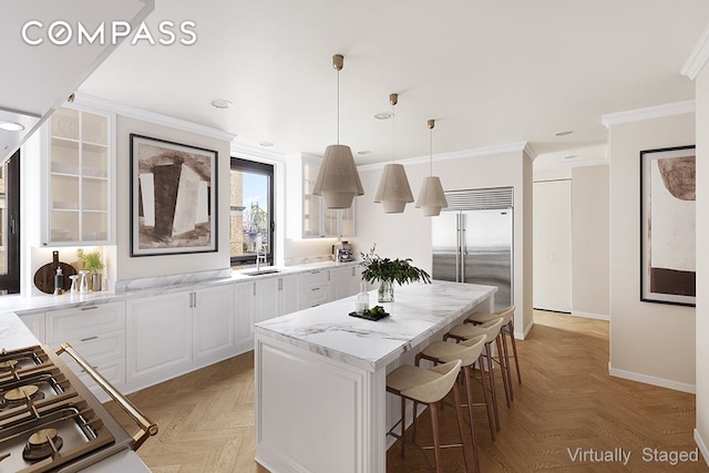 kitchen with a kitchen island, crown molding, glass insert cabinets, a breakfast bar area, and built in fridge