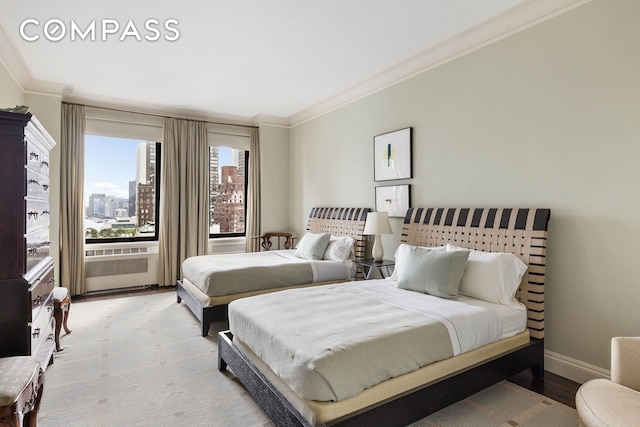 bedroom with a city view, light wood-type flooring, baseboards, and ornamental molding