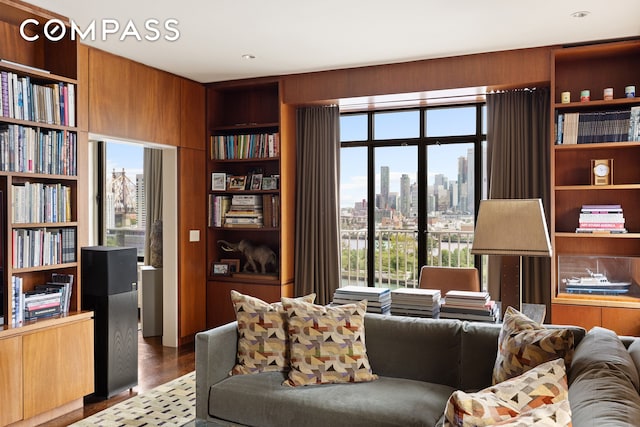 living area with a view of city, a healthy amount of sunlight, and wood finished floors