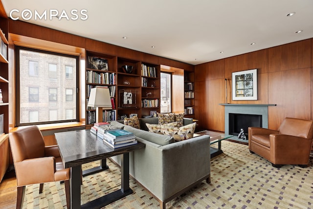 living room with a fireplace with flush hearth, recessed lighting, wood walls, and built in features