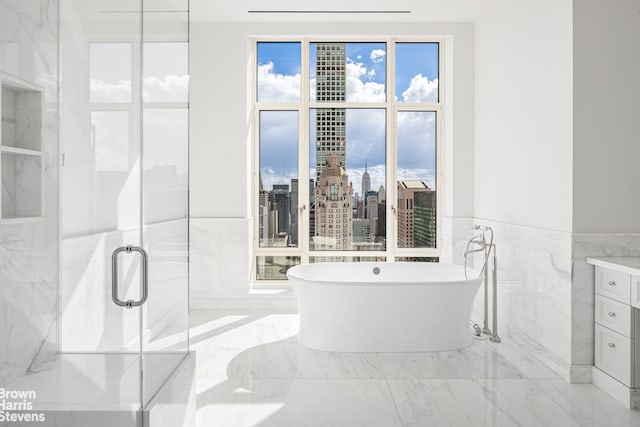 full bathroom with a marble finish shower, a city view, plenty of natural light, a soaking tub, and marble finish floor