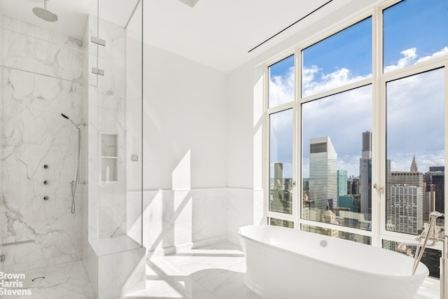 full bath with a freestanding tub, marble finish floor, a city view, a marble finish shower, and tile walls