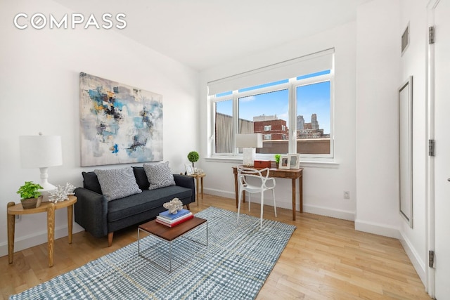 interior space featuring a view of city, baseboards, visible vents, and light wood finished floors