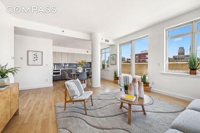 living room featuring a view of city, baseboards, visible vents, and light wood finished floors