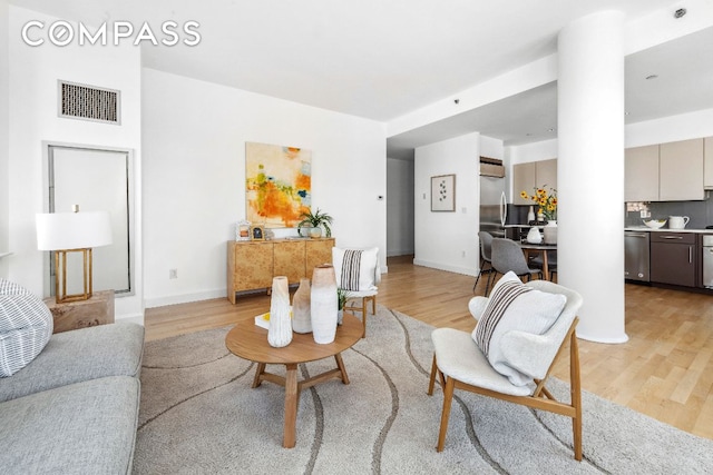 living room with baseboards, visible vents, and light wood-style floors