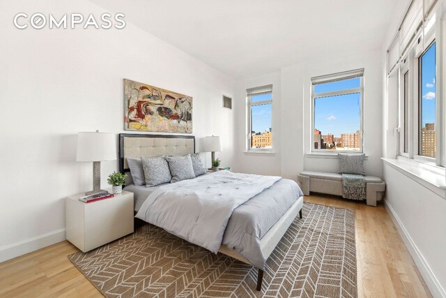 bedroom with visible vents, a city view, baseboards, and wood finished floors