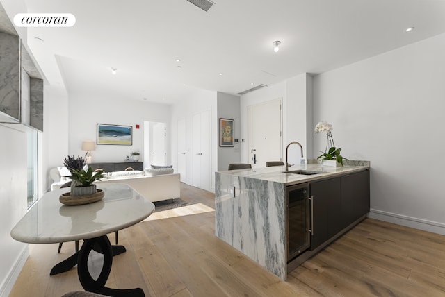 kitchen with light hardwood / wood-style floors, sink, beverage cooler, and kitchen peninsula