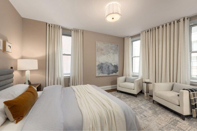 bedroom with multiple windows, baseboards, and light wood-type flooring