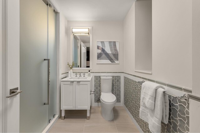bathroom featuring toilet, tile patterned flooring, vanity, and a wainscoted wall