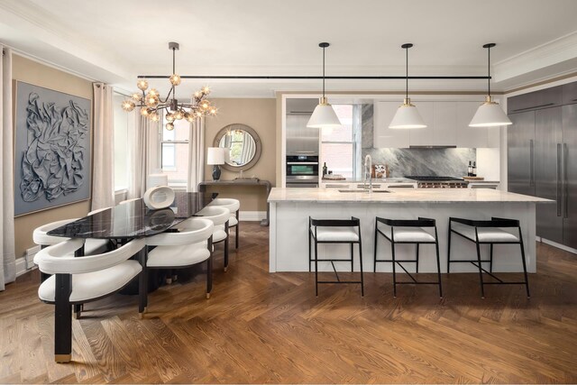 kitchen with appliances with stainless steel finishes, crown molding, tasteful backsplash, a spacious island, and a chandelier