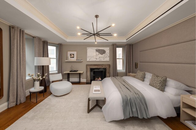 bedroom with wood finished floors, a chandelier, a tray ceiling, ornamental molding, and recessed lighting