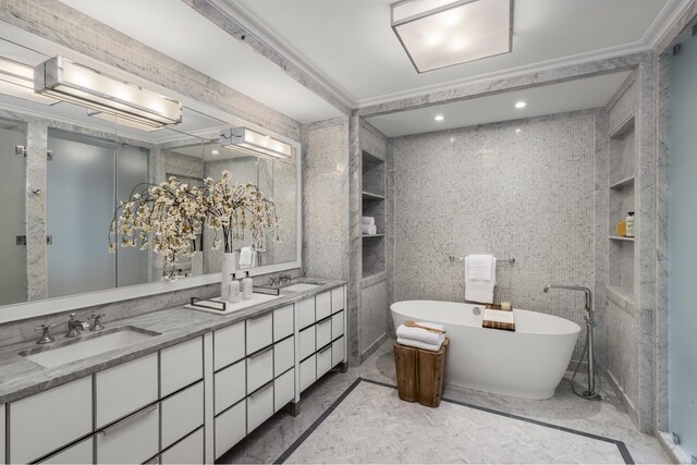 full bath featuring marble look tile flooring, a soaking tub, double vanity, and crown molding