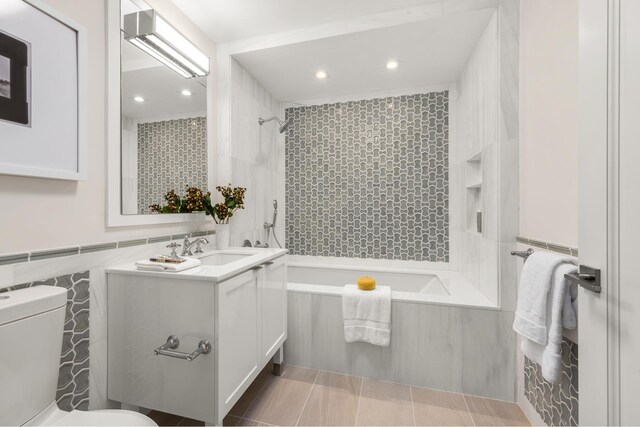 bathroom with toilet, shower / bathtub combination, tile walls, vanity, and recessed lighting