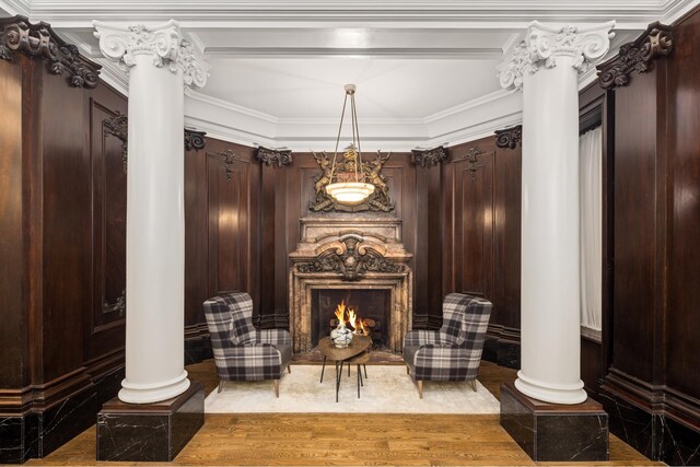 living area featuring decorative columns, wood finished floors, and a fireplace