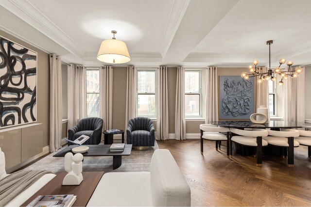 living area with a raised ceiling, a chandelier, baseboards, and crown molding