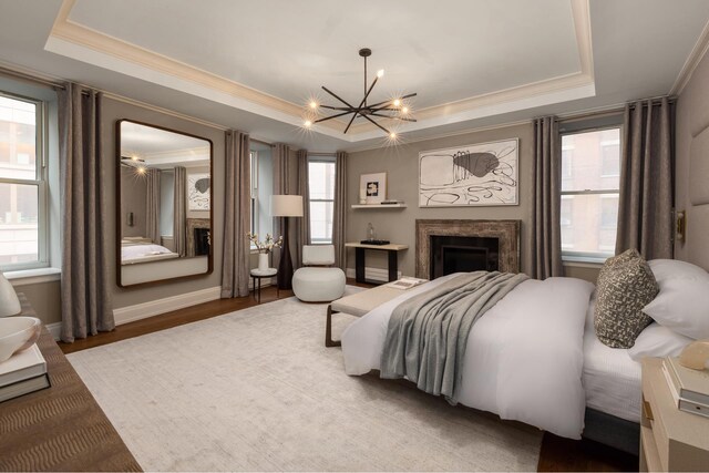 bedroom featuring a tray ceiling, crown molding, a chandelier, a fireplace, and multiple windows