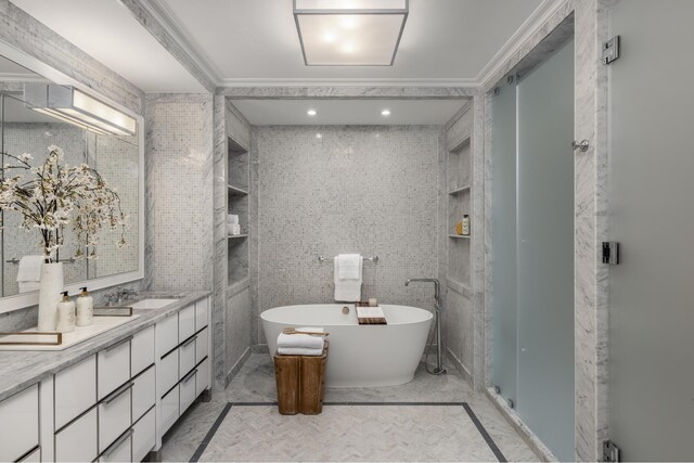 full bath featuring a freestanding bath, vanity, tile walls, and ornamental molding