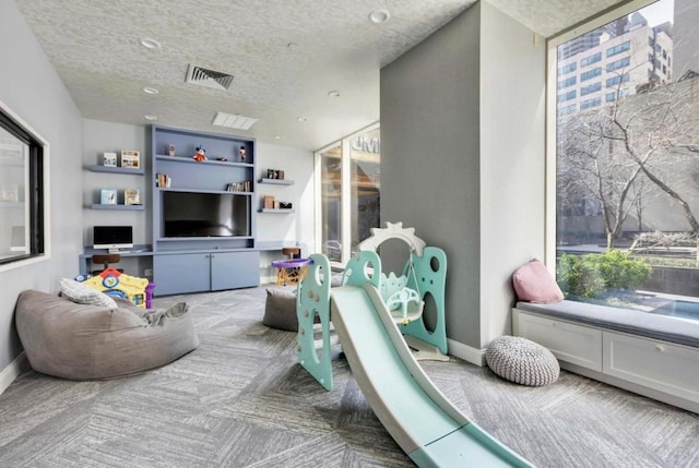 rec room with floor to ceiling windows, carpet floors, and a textured ceiling