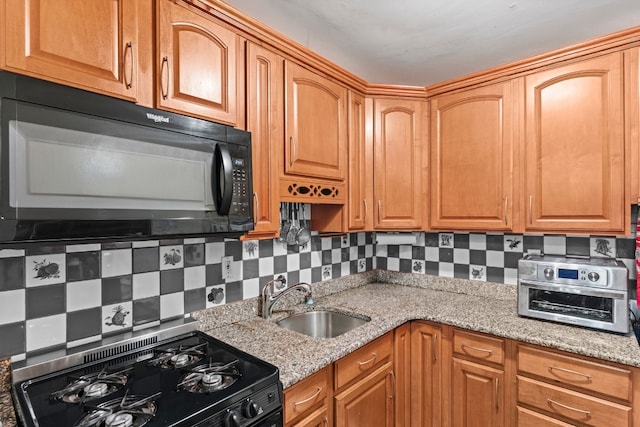 kitchen with black appliances, light stone countertops, sink, and decorative backsplash