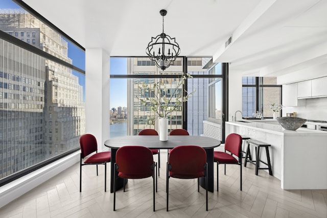 dining space with light parquet floors, a water view, a notable chandelier, and a wall of windows