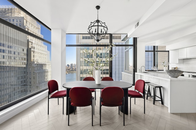 dining room with a notable chandelier, floor to ceiling windows, visible vents, and a city view