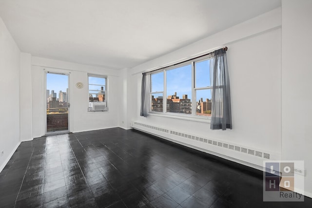 spare room featuring a baseboard heating unit, a view of city, and baseboards