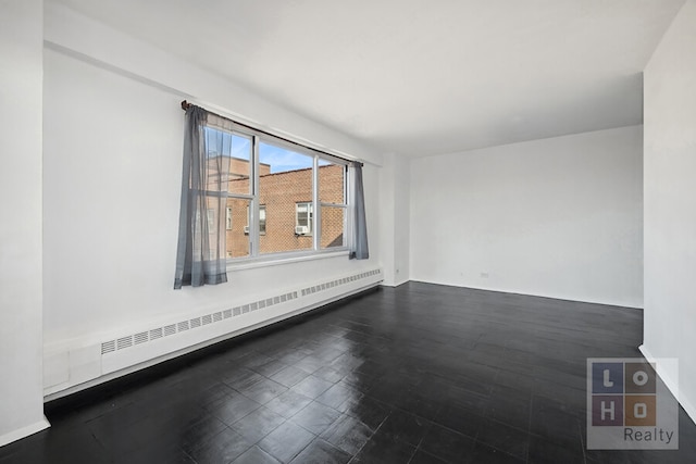 spare room with a baseboard radiator and dark wood finished floors