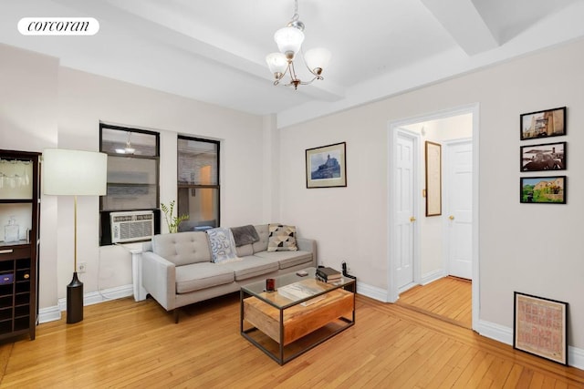 living room with a notable chandelier, beam ceiling, cooling unit, and light hardwood / wood-style flooring